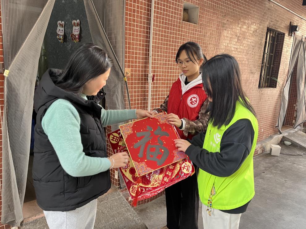 社工与志愿者向居民展示学生书写的“福”字.jpg
